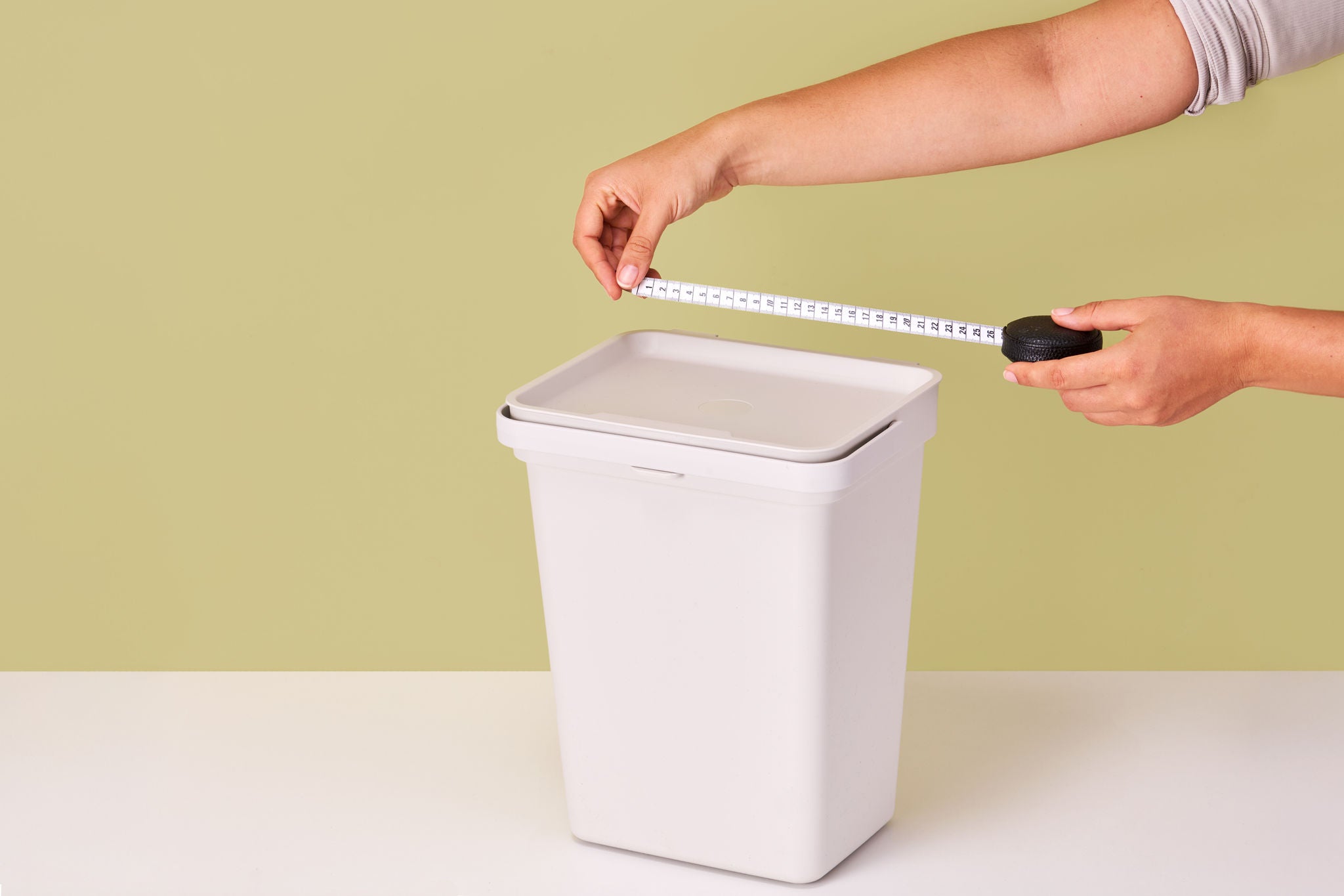 Hände messen mit Maßband Mülleimer-Breite aus